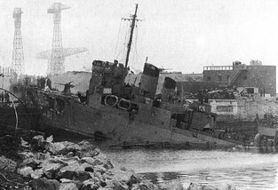 HMS Campbeltown resting on the caisson of the dry dock before the explosives detonated killing at least 450 high ranking German Officers and civilians inspecting the vessel. 